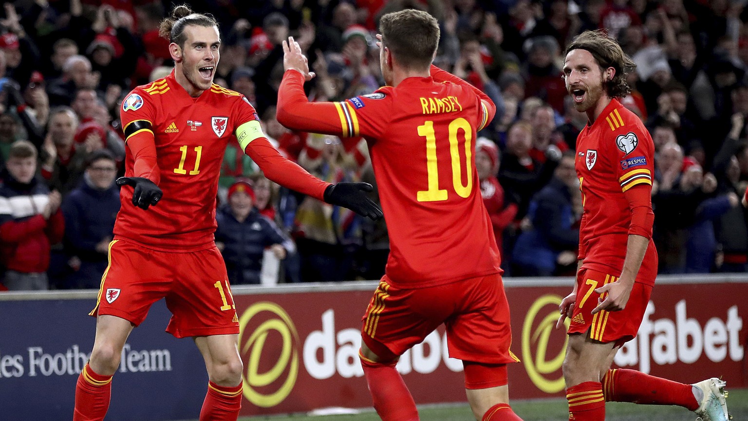 Wales' Aaron Ramsey celebrates scoring his side's first goal of the game against Hungary, with team-mates Gareth Bale, left, and Joe Allen, right, during their UEFA Euro 2020 Qualifying socc ...