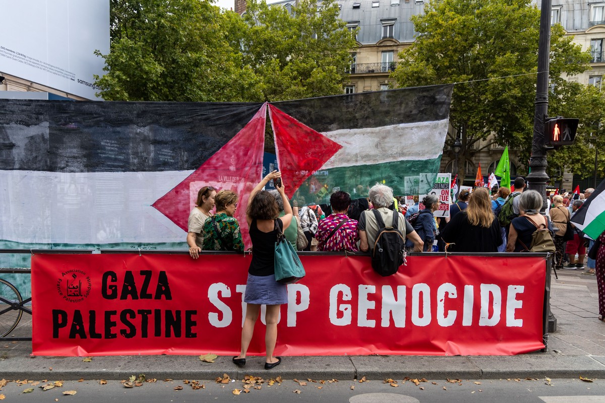 epa12310778 Demonstrators gather on Saint Michel square behind a banner reading ?Gaza Palestine Stop genocide', during a solidarity rally for Gaza and Palestine in Paris, France, 19 August 2025.  ...
