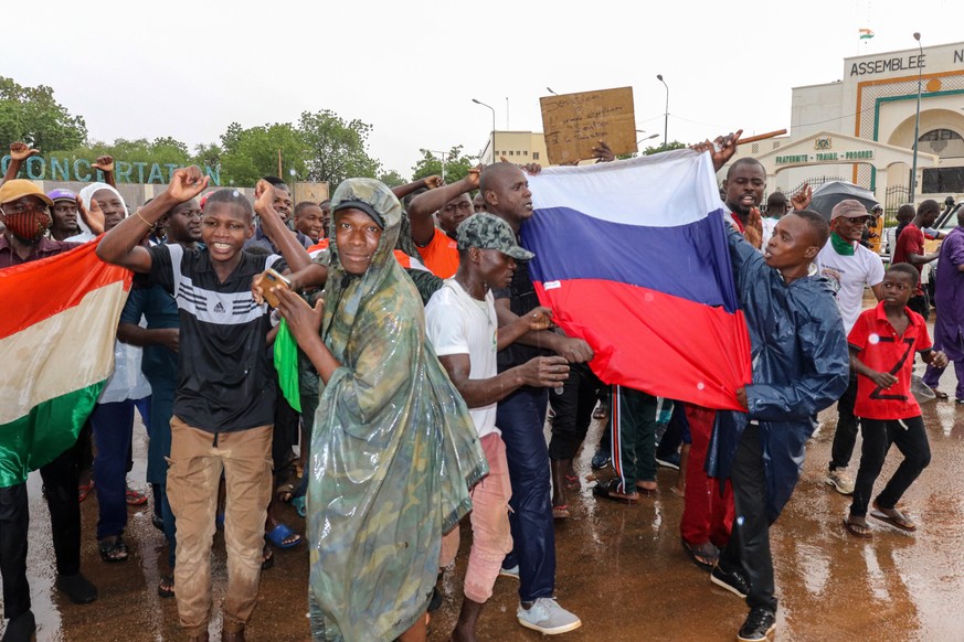 epa10771230 Supporters of putschist soldiers hold Niger&#039;s and Russia&#039;s flags as they celebrate outside the National Assembly building in Niamey, Niger, 27 July 2023. Mutinous soldiers callin ...