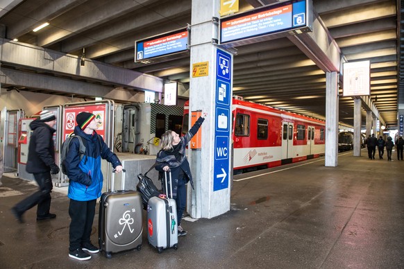 epa06427274 People with suitcases look at the infoscreen showing cancelled routes at the empty bus station in Zermatt, Switzerland, 09 January 2018. Due to heavy snowfall and rain showers, Zermatt can ...