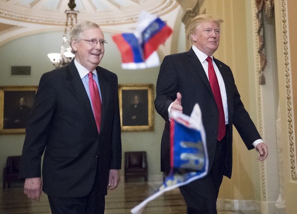 Small Russian flags bearing the word &quot;Trump&quot; are thrown by a protester toward President Donald Trump, as he walks with Senate Majority Leader Mitch McConnell, R-Ky., on Capitol Hill to have  ...