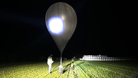 In this undated photo released by the State Border Guard Service, an officer inspects a balloon used to carry cigarettes into Lithuania, because Belarussian smugglers often use them to ferry the contr ...