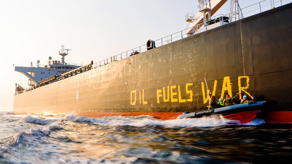 Activists of the environmental organization Greenpeace paint the words &#039;Oil fuels war&#039; on the hull of a ship carrying Russian oil near the German island Fehmarn, Germany, Wednesday, March 23 ...