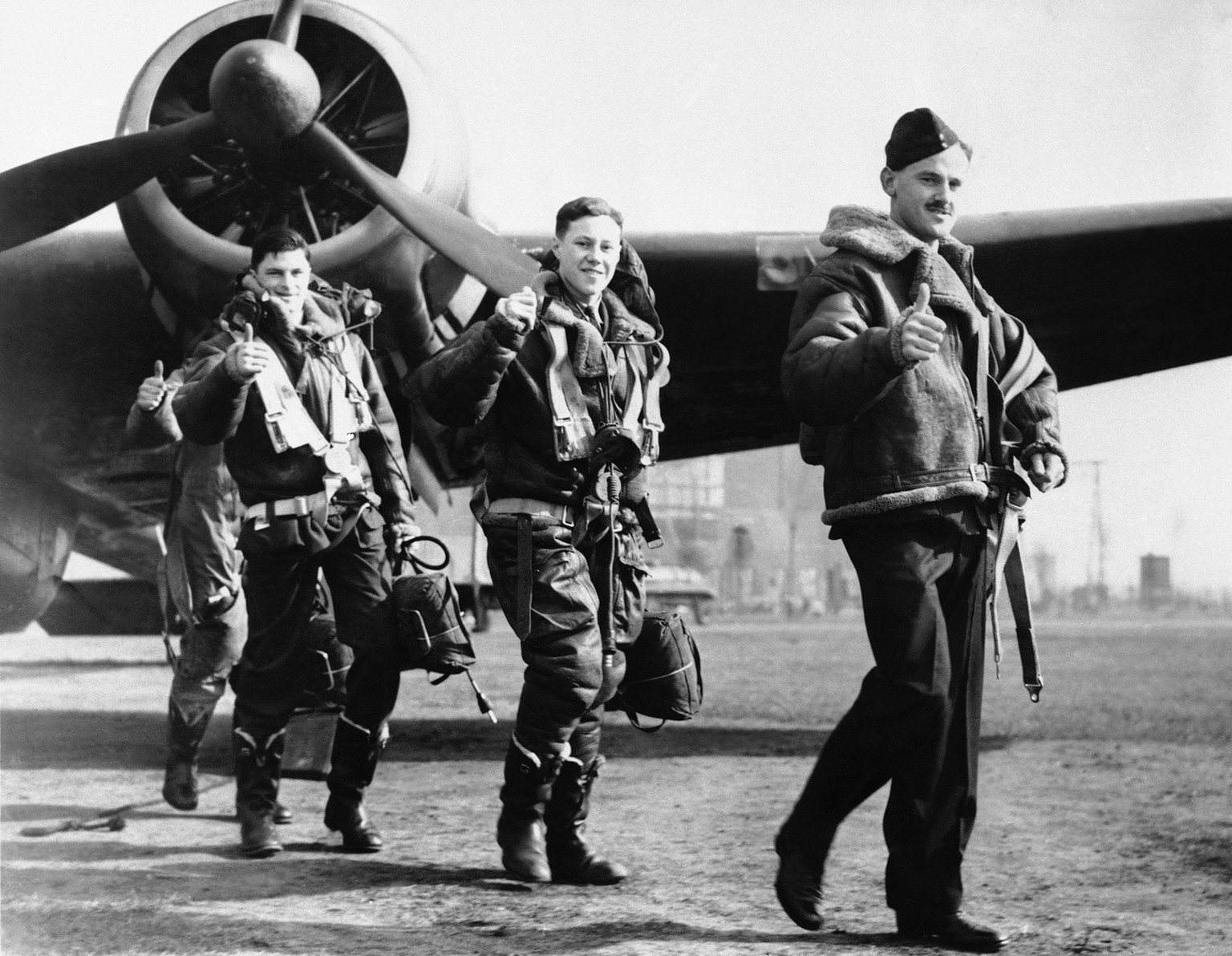 These members of a British Royal Air force bombing squadron hold thumbs up ñ A gesture signifying a Nazi warship has been sunk ñ as they return to their home base, April 22, 1940, from an attack on Ge ...