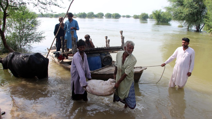 epa10145597 People carry furniture through a flooded area following heavy rains in Larkana, Sindh province, Pakistan, 29 August 2022. According to the National Disaster Management Authority (NDMA) on ...