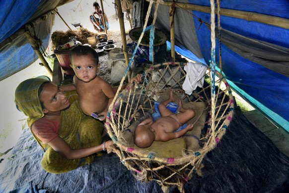 epa04358783 A woman takes care of her young children in a makeshift camp in the flood affected Morigaon district of Assam state, India, 18 August 2014. Dozens of people were killed and more than a mil ...