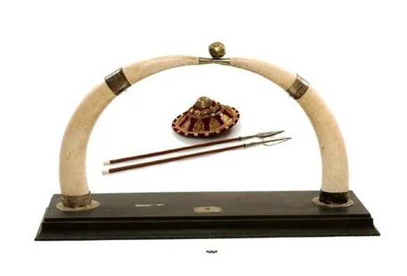 Die Geschenke an die Stadt Genf: Montierte Elefantentrophäen, zwei äthiopische Speere und dazu ein Schild.
https://collections.geneve.ch/meg/catalogue/musinfo_public.php?id=025606