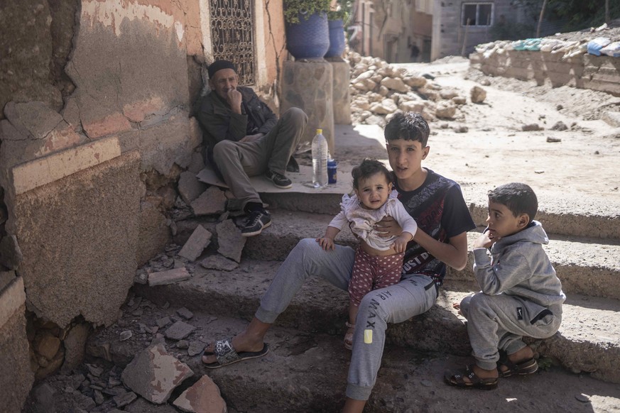 CORRECTS NAME OF VILLAGE A family sits outside their home after an earthquake in Moulay Brahim village, near Marrakech, Morocco, Saturday, Sept. 9, 2023. A rare, powerful earthquake struck Morocco lat ...