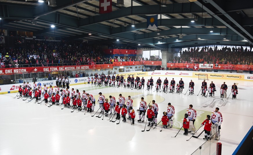 The teams of Switzerland and Slovakia line up for the national anthem prior to the ice hockey gold medal game (final) of the Arosa Challenge, on Saturday, December 19, 2015, in Arosa, Switzerland. (KE ...