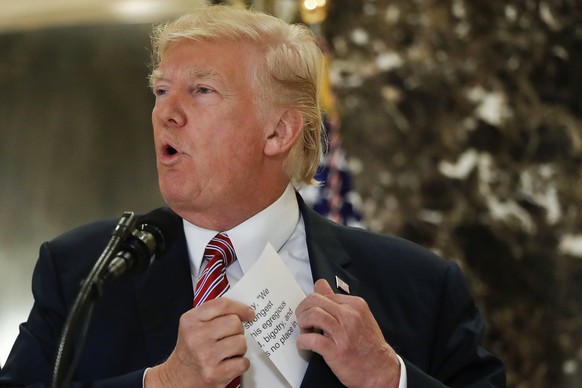 President Donald Trump reaches into his suit jacket Tuesday, Aug. 15, 2017 to read a quote he made on Saturday, Aug. 12, regarding the events in Charlottesville, Va., as he speaks to the media in the  ...