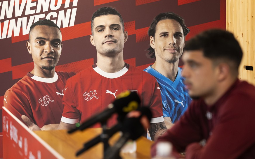 Zeki Amdouni spricht bei einer Pressekonferenz der Schweizer Fussball Nationalmannschaft neben einem Plakat mit Manuel Akanji, Granit Xhaka und Yann Sommer, im Vorbereitungscamp zur Europameisterschaf ...