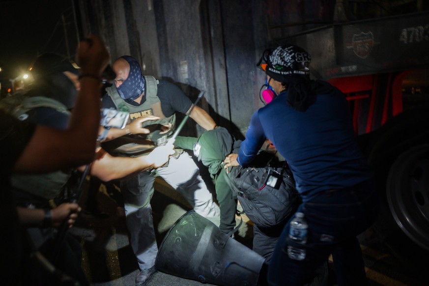 epa12999393 Immigration and Customs Enforcement (ICE) agents chase protesters onto the road where they nearly get hit by a truck during a protest against the treatment of detainees at the Delaney Hall ...