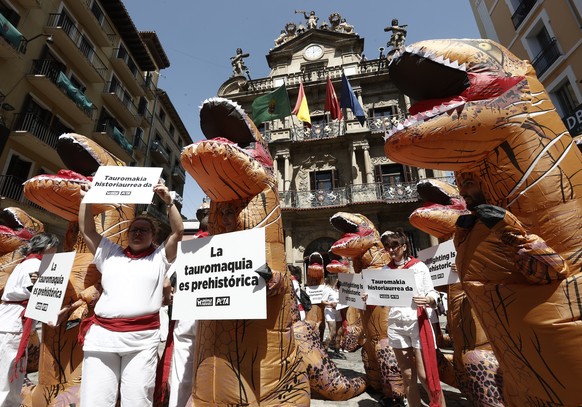 epa10053307 Animal rights activists from AnimaNaturalis and PETA organizations pose disguised as dinosaurs in front of the City Council of Pamplona during a protest against bullfighting and the upcomi ...