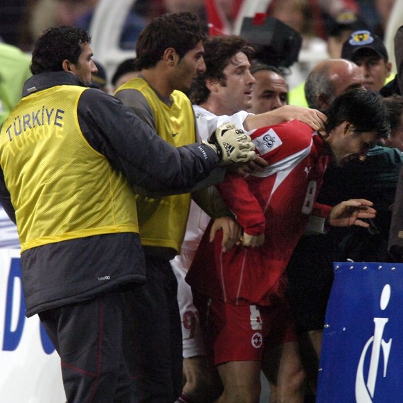 Swiss player Raphael Wicky, right, is grabbed by the neck by Turkish Tekke Fatih, center, leaving the pitch after the final whistle of the FIFA 2006 qualifying play-off second leg soccer match between ...
