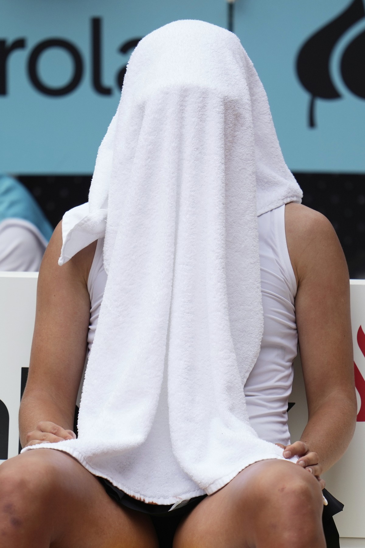 Iga Swiatek of Poland covers her face with a towel during her match against United States' Madison Keys at the Madrid Open tennis tournament in Madrid, Spain, Wednesday, April 30, 2025. (AP Photo ...