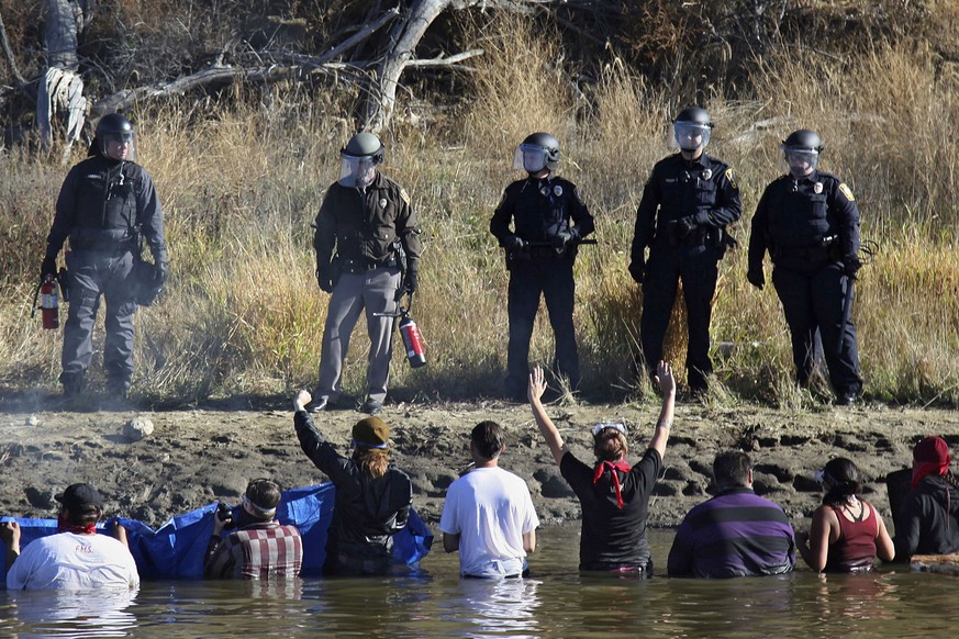 FILE - In this Nov. 2, 2016 file photo, dozens of protestors demonstrating against the expansion of the Dakota Access Pipeline wade in cold creek waters confronting local police, near Cannon Ball, N.D ...