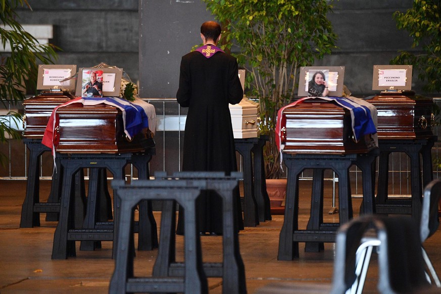 epa06954152 A bishop blesses the coffin of a victim of a collapsed highway bridge at the Fiera di Genova exhibition cente, where some of the victims are laid in state, in Genoa, Italy, 17 August 2018. ...