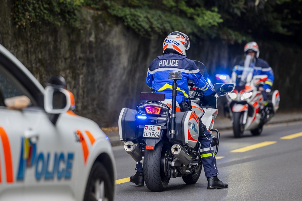 Une voiture police et des motards de la police genevoise, avec leurs feux bleus, signalent la presence d'une manifestation aux automobilistes, ce samedi 13 septembre 2025 a Geneve. (KEYSTONE/Salv ...