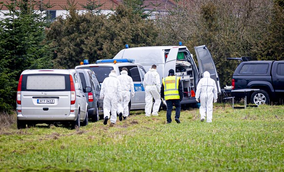 25.01.2023, Niedersachsen, Wunstorf: Mitarbeiter der Spurensicherung der Polizei gehen �ber eine Wiese, vorbei an einem Leichenwagen. Auf der Suche nach einer mutma�lich get�teten Person haben Einsatz ...