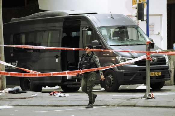 An Israeli border police officer walks at the scene of a shooting attack near the Shuafat refugee camp in Jerusalem, Saturday, Oct. 8, 2022. Israeli police say armed assailants have opened fire at an  ...