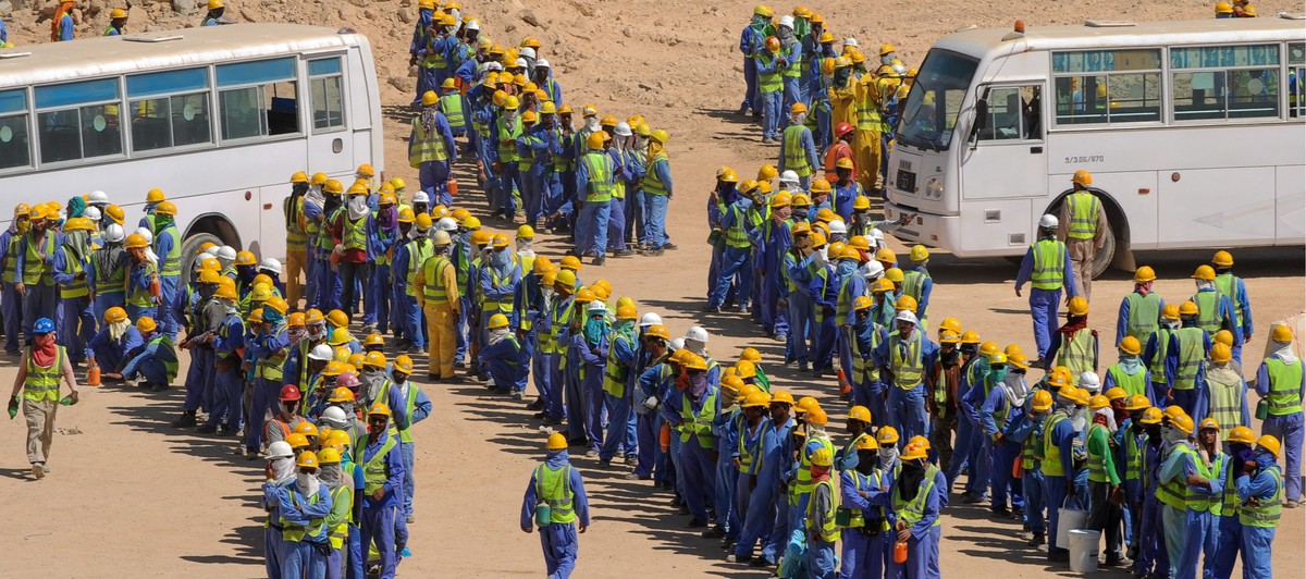 epa03956764 Foreign construction workers queue up for the bus back to their accommodation camp in Doha, Qatar, 19 November 2013. The previous day, football's ruling body FIFA said it will continu ...