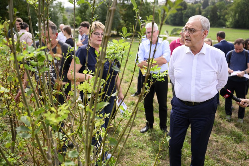 Le conseiller federal et president de la Confederation Guy Parmelin, droite, observe avec Sabine Bach, centre, et son mari Nicolas, gauche, responsable de l'exploitaion agricole de la Ferme Comex ...