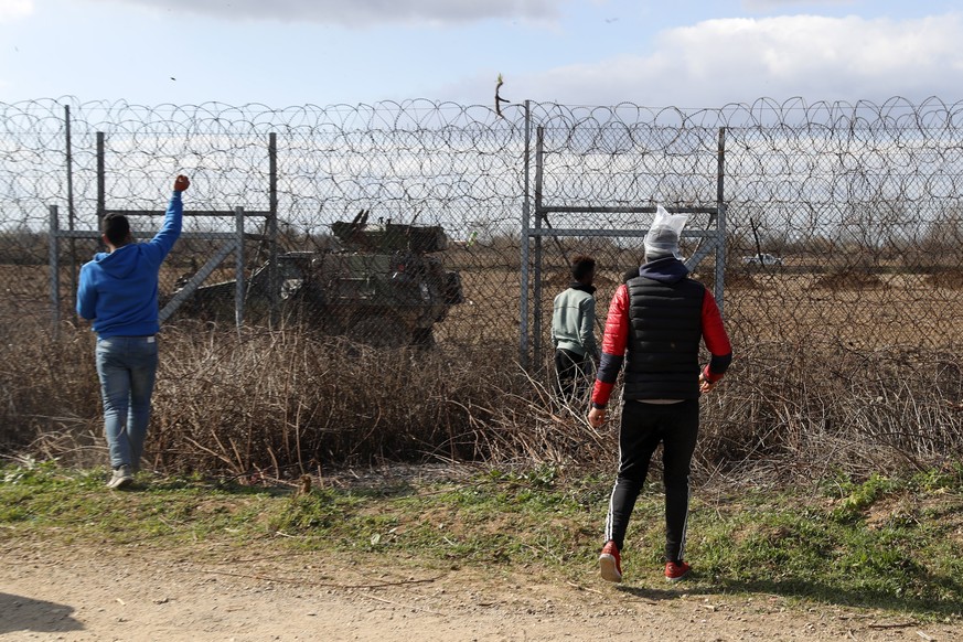 Migrants gather at a border fence on the Turkish side during clashes with the Greek riot police at the Turkish-Greek border in Pazarkule, Edirne region, on Saturday, March 7, 2020. Thousands of refuge ...