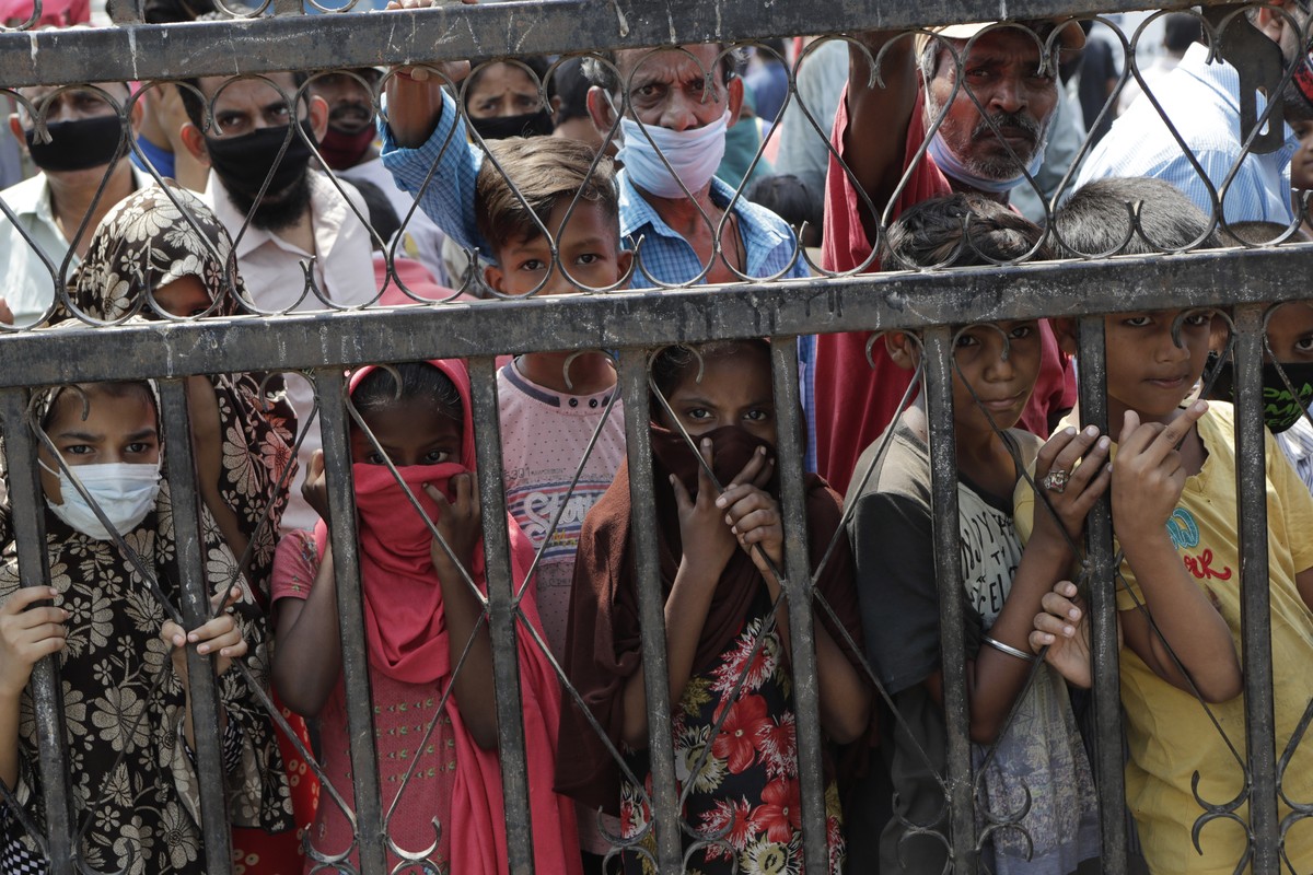Children wait to receive food distributed in a slum during a lockdown due to the coronavirus pandemic in Mumbai, India, Saturday, April 18, 2020. The organization says they serve thousands of people d ...