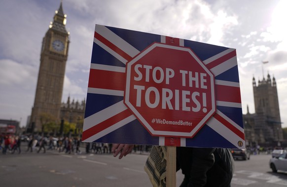 A placard saying &quot;Stop the Tories&quot; is held by a demonstrator outside the Houses of Parliament, in London, Wednesday, Oct. 19, 2022. Since the shock 2016 referendum vote to leave the European ...