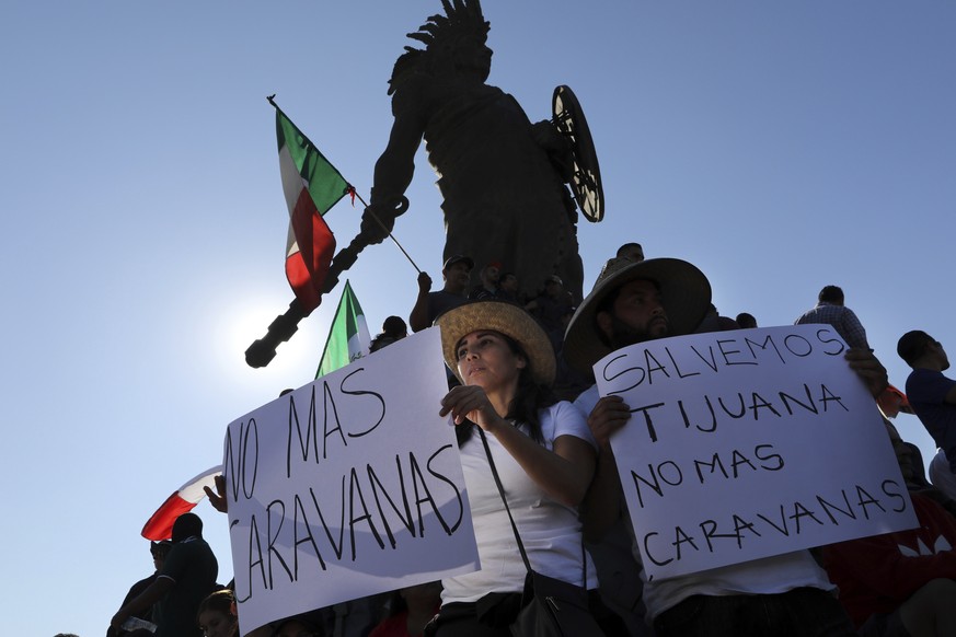 Demonstrators with signs that read in Spanish: &quot;No more Caravans&quot;, and &quot;Let&#039;s save Tijuana, no more caravans,&quot; stand under an statue of indigenous Aztec ruler Cuauhtemoc to pr ...
