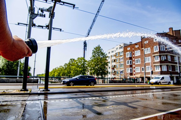 epa07739600 A city worker sprays water over the Wiegbrug in Amsterdam, the Netherlands, 25 July 2019. The Royal Dutch Meteorology Institute (KNMI) has issued an official warning due to the warm weathe ...