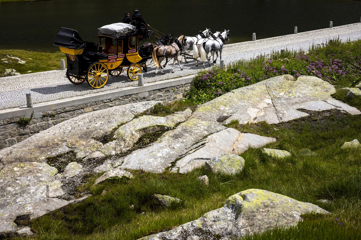 The historic Gotthard stagecoach 'Gotthardpost' pulled by five horses travels along the old Tremola Pass road on the Gotthard Pass while traffic is jammed in the valley in front of the Gotth ...