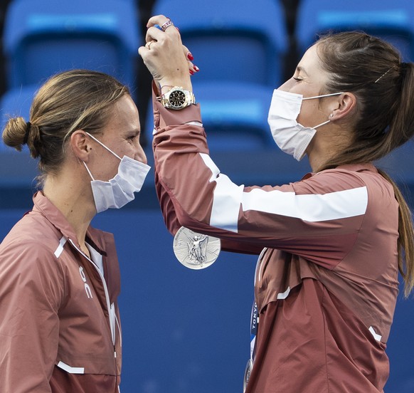 Switzerland&#039;s Belinda Bencic, right, hands over the silver medal to her teammate Viktorija Golubic during the women&#039;s tennis doubles gold medal match against Barbora Krejcikova and Katerina  ...