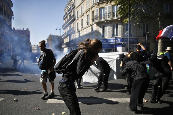 Protestors protect themselves from teargas during a climate demonstration, in Paris, Saturday, Sept. 21, 2019. Scuffles broke out in Paris between some violent activists and police which responded wit ...