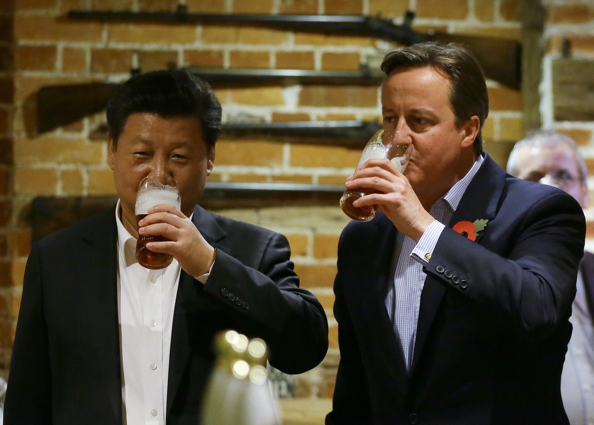 Britain's Prime Minister David Cameron, centre right, drinks beer with Chinese President Xi Jinping, at a pub in Princess Risborough, near Chequers, England, Thursday, Oct. 22, 2015. The two lead ...
