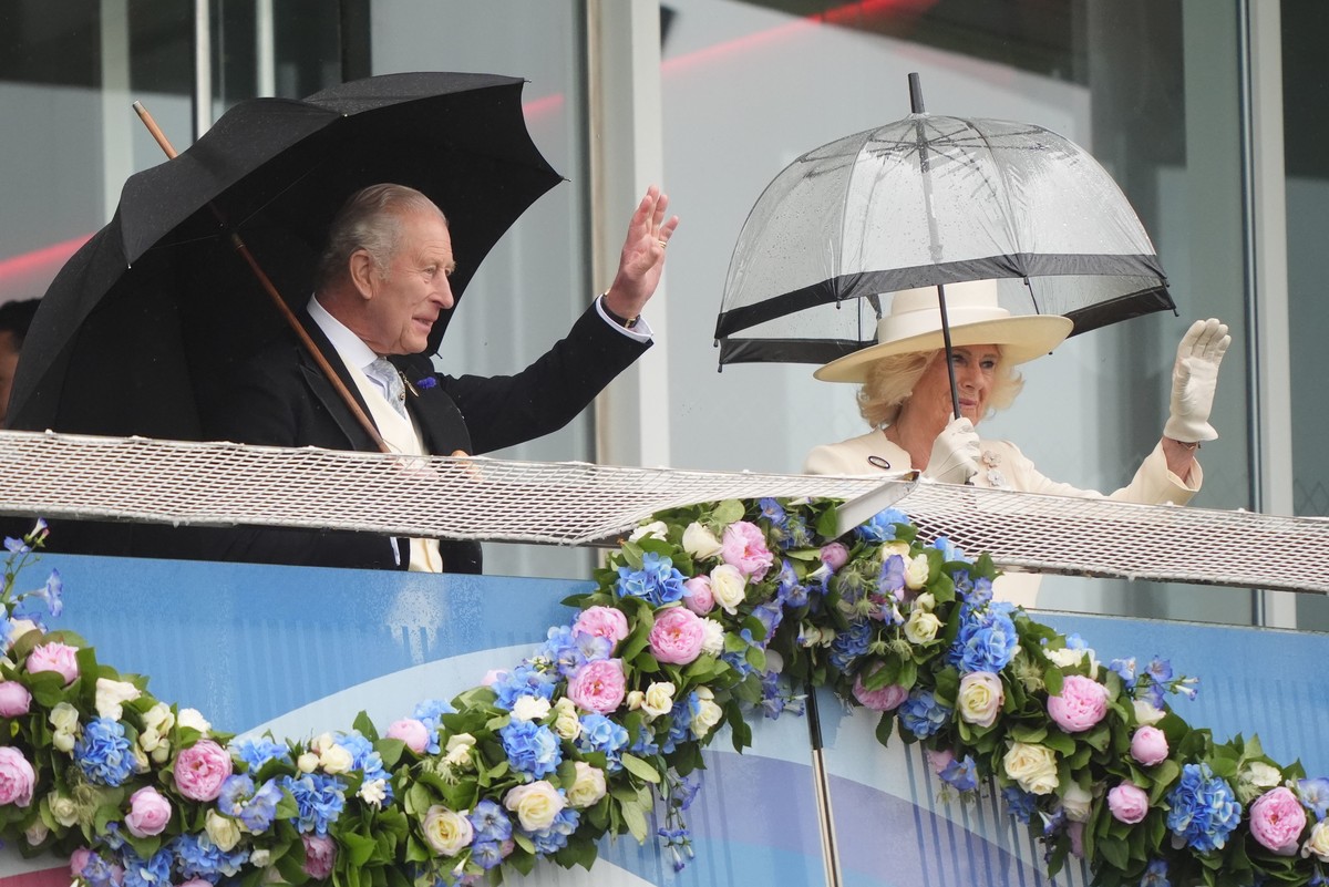Britain's King Charles III and Queen Camilla wave to the crowd from the royal box during Derby Day of the Betfred Derby Festival at Epsom Downs Racecourse, England, Saturday June 6, 2026. (Jonath ...