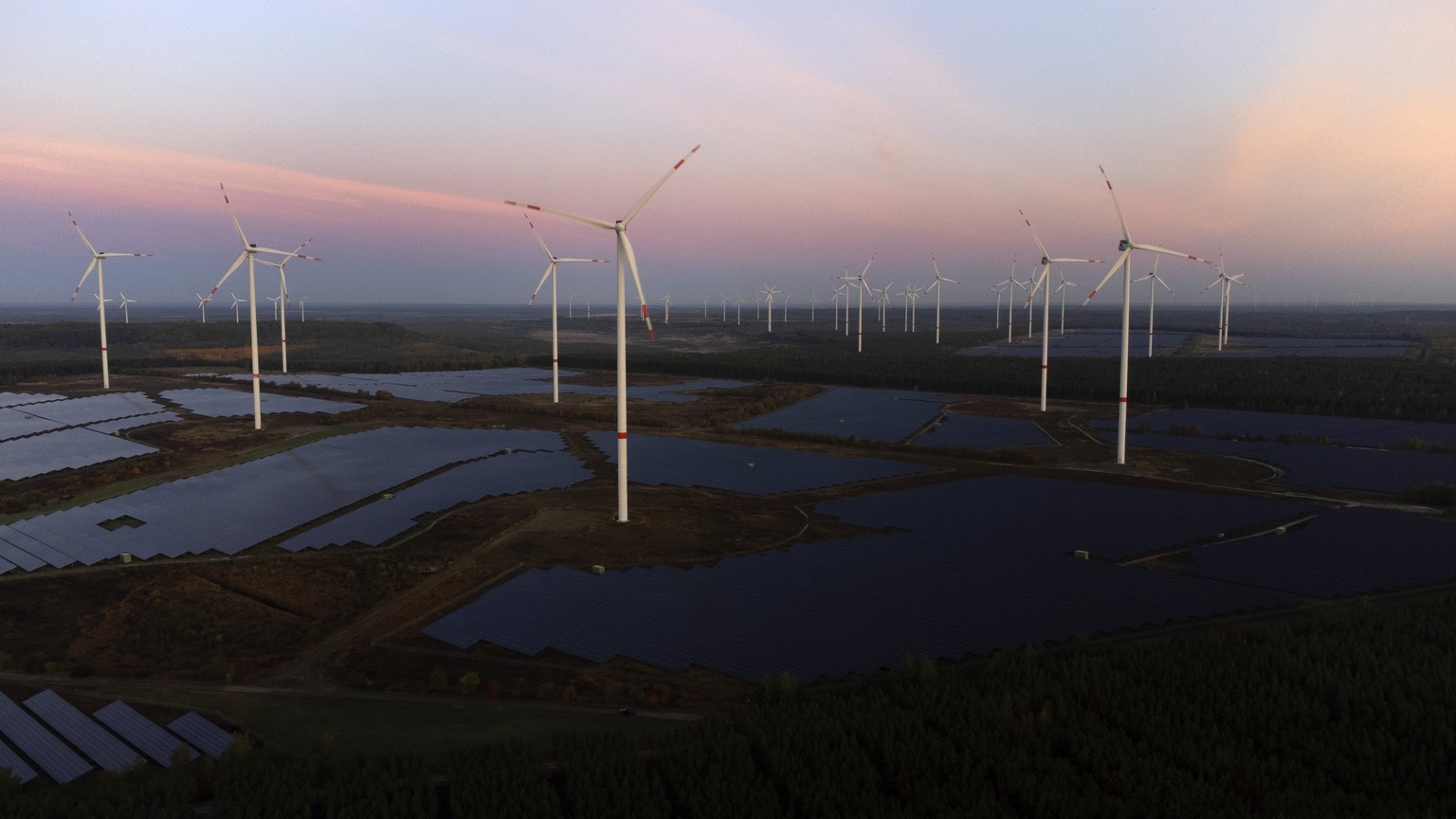FILE - Wind turbines operate as the sun rises at the Klettwitz Nord solar energy park near Klettwitz near Klettwitz, Germany, Oct. 16, 2024. (AP Photo/Matthias Schrader, File)