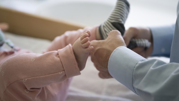 ZUM THEMA VATERSCHAFTSURLAUB STELLEN WIR IHNEN HEUTE, MITTWOCH, 25. OKTOBER 2017, FOLGENDES BILDMATERIAL ZUR VERFUEGUNG --- A father dresses his five-month-old daughter, pictured in Kilchberg, Canton  ...