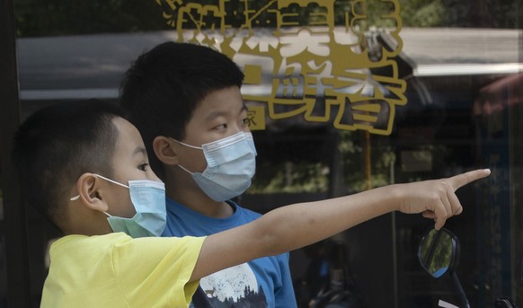 Children wearing masks to curb the spread of the new coronavirus chat outside a restaurant in Beijing on Friday, June 19, 2020. China declared a fresh outbreak in Beijing under control after numbers f ...