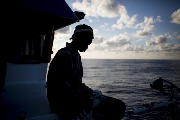In this Friday, Nov. 30, 2018, photo, a migrant from Senegal sits on the deck of a the Nuestra Madre de Loreto Spanish fishing vessel carrying 12 migrants rescued off the coast of Lybia. One of the mi ...
