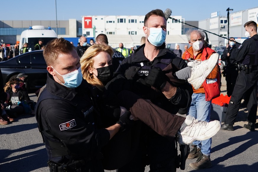 epa09842277 Policemen remove an activist as they block an entrance during the opening day of the Tesl Gigafactory in Gruenheide near Berlin, Germany, 22 March 2022. German Chancellor Olaf Scholz is ex ...