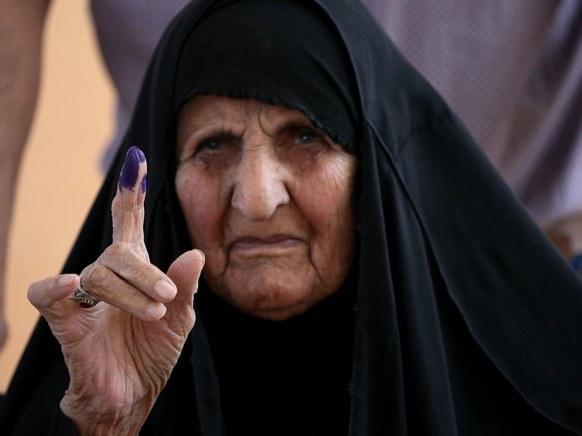 An Iraqi woman shows her ink-stained finger after casting her vote during parliamentary elections, inside a polling station in Najaf, Iraq, Sunday, Oct. 10, 2021. Iraq closed its airspace and land bor ...