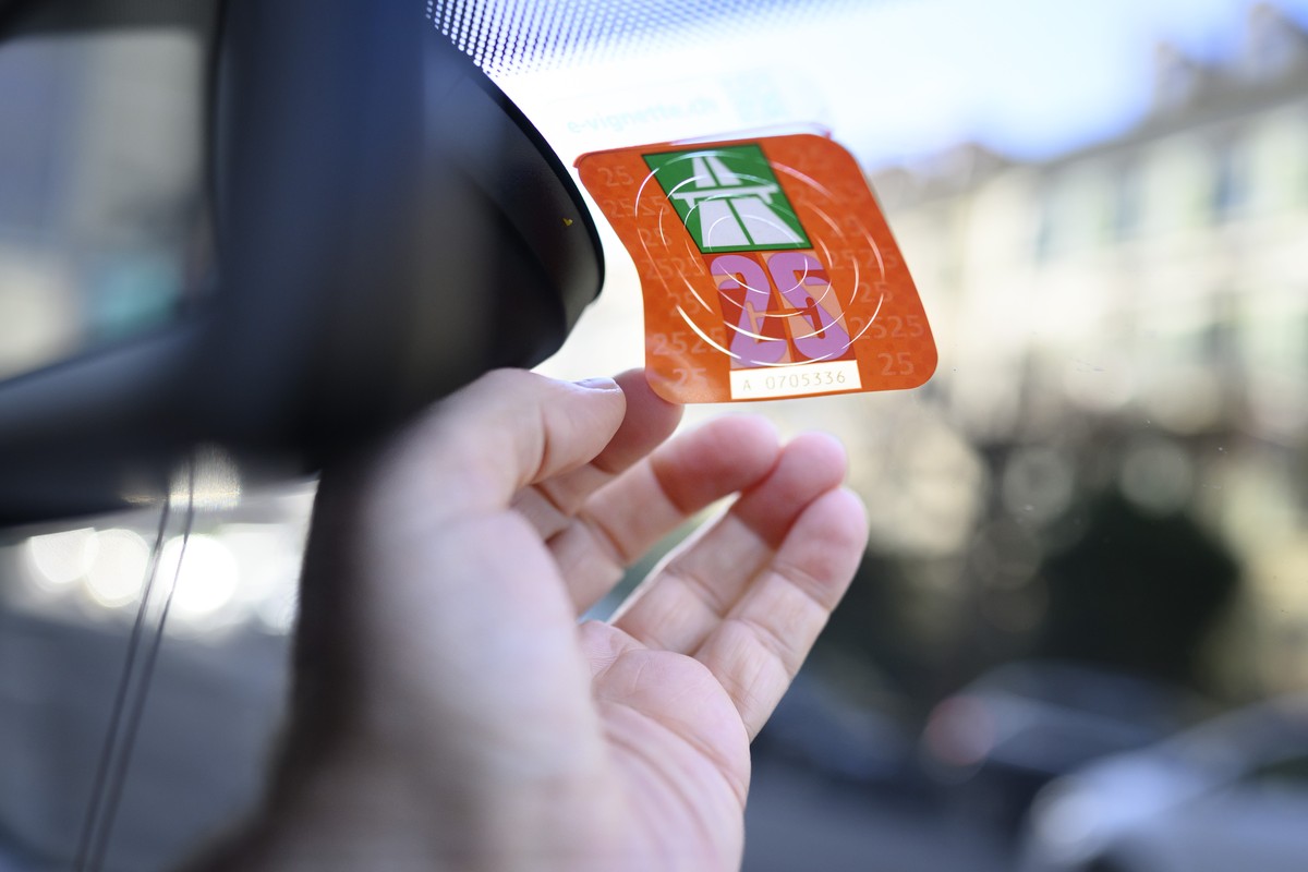 Ein Mann klebt eine Autobahnvignette fuer das Jahr 2025 auf die Windschutzscheibe eines Autos, fotografiert am Freitag, 6. Dezember 2024 in Bern. (KEYSTONE/Christian Beutler)