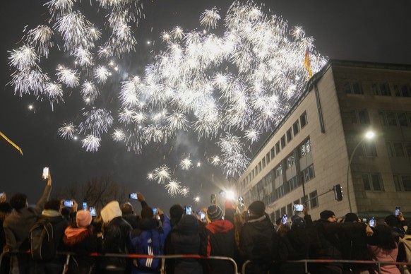 Spectators at the boulevard Unter den Linden watch fireworks as they celebrate the New Year near the Brandenburg Gate in Berlin, Germany, Saturday, Jan. 1, 2022. Large-scale New Year celebrations are prohibited in Germany. (AP Photo/Markus Schreiber)