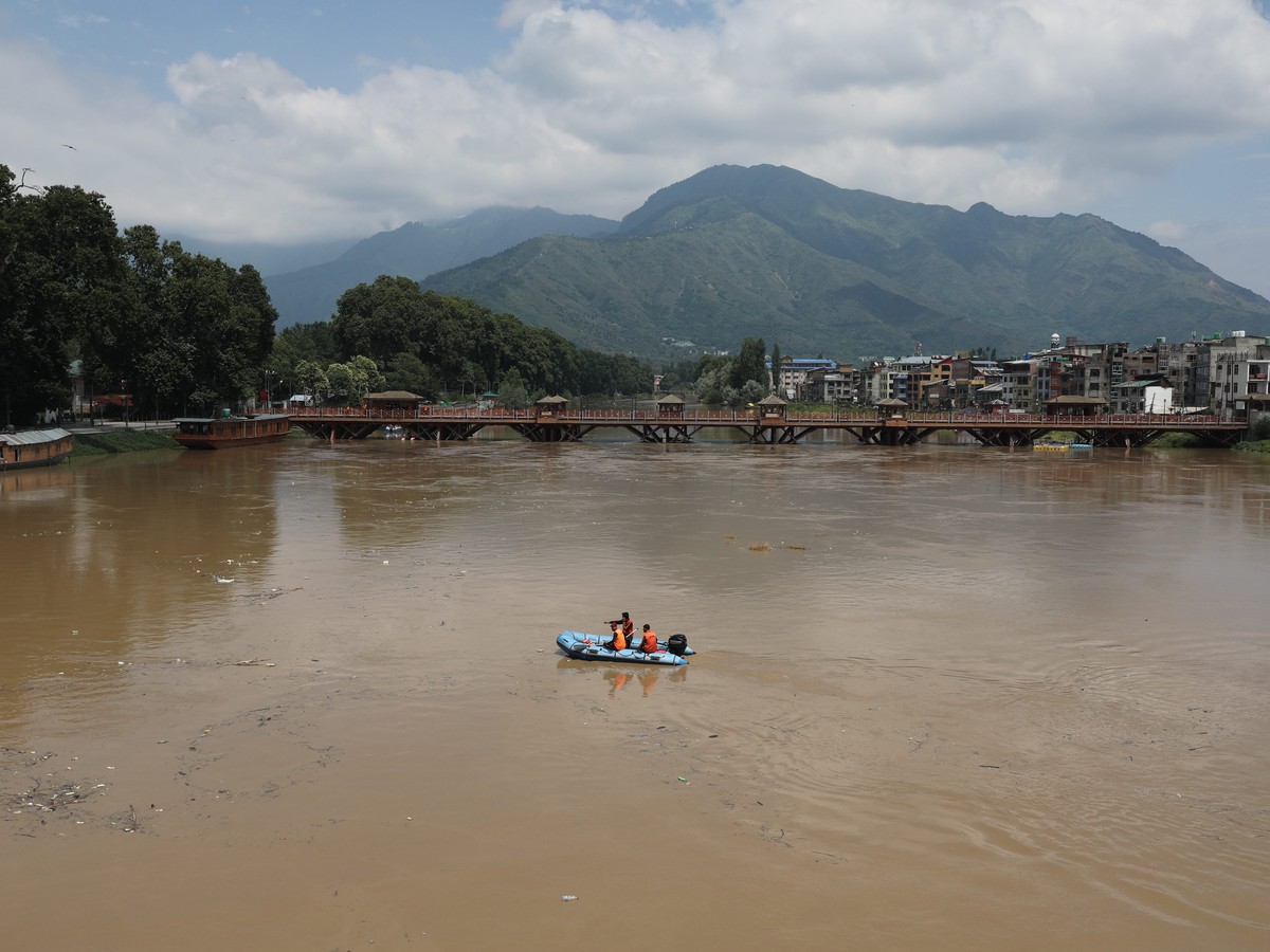 epa10736544 Indian police officers patrol on a boat on Jhelum river in Srinagar, the summer capital of Indian Kashmir, 09 July 2023. The threat of flooding in Kashmir was averted on 09 July as the wat ...