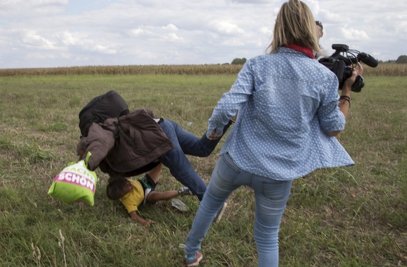 REFILE - ADDITIONAL INFORMATIONA migrant carrying a child falls after tripping on TV camerawoman (R) Petra Laszlo while trying to escape from a collection point in Roszke village, Hungary, September 8 ...