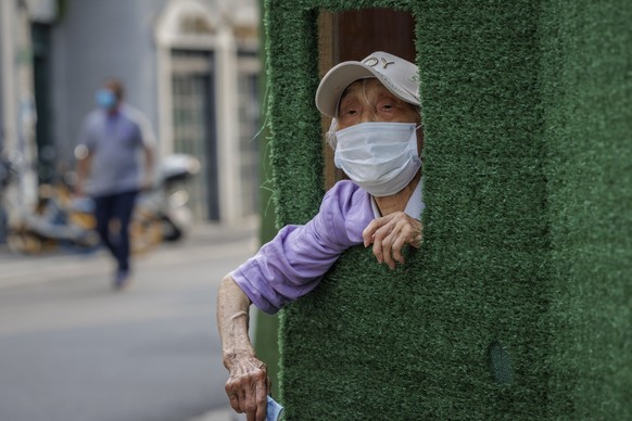 epaselect epa10066408 A woman asks people passing-by to buy her food through the opening in quarantine barrier, in Shanghai, China, 12 July 2022. Shanghai city reported five locally transmitted COVID- ...