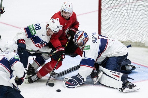 Switzerland&#039;s Damien Riat, center, in action against United States&#039; Nate Schmidt, left, and goalkeeper Jeremy Swayman during the Ice Hockey World Championship quarter final match between Swi ...