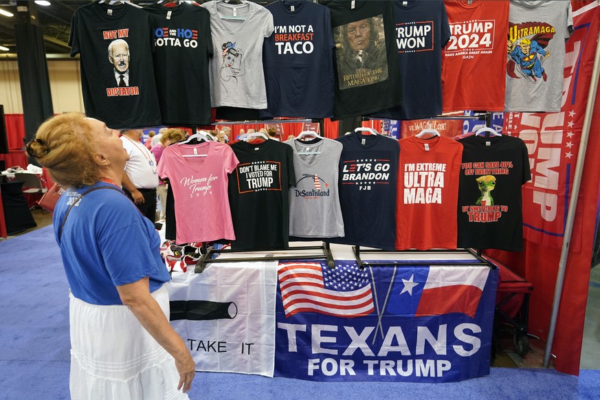 Maura C Jans of Rio Rancho, N.M., laughs as she looks at T-shirts for sale at the Conservative Political Action Conference (CPAC) in Dallas, Thursday, Aug. 4, 2022. Hungarian Prime Minister Viktor Orb ...