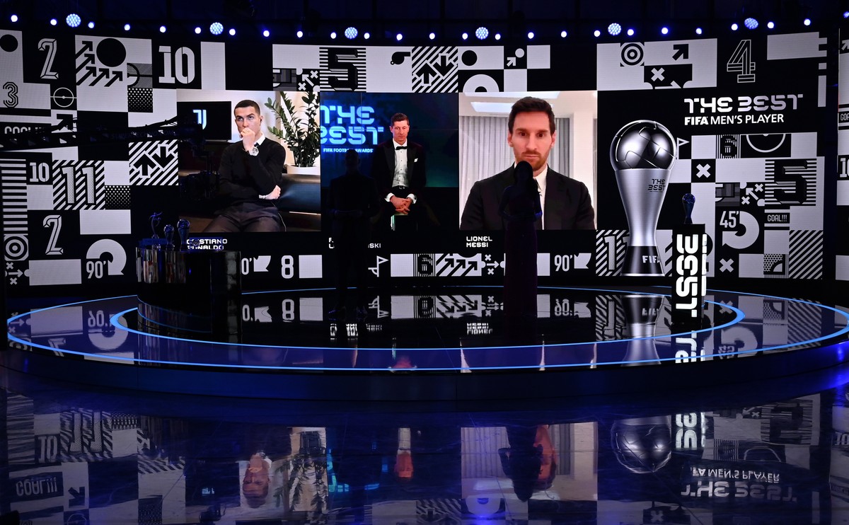 epa08890532 Bayern Munich striker Robert Lewandowski (C on screen) appears on screen with fellow finalists Cristiano Ronaldo (L) and Lionel Messi after receiving the Best FIFA Men's Player Award  ...